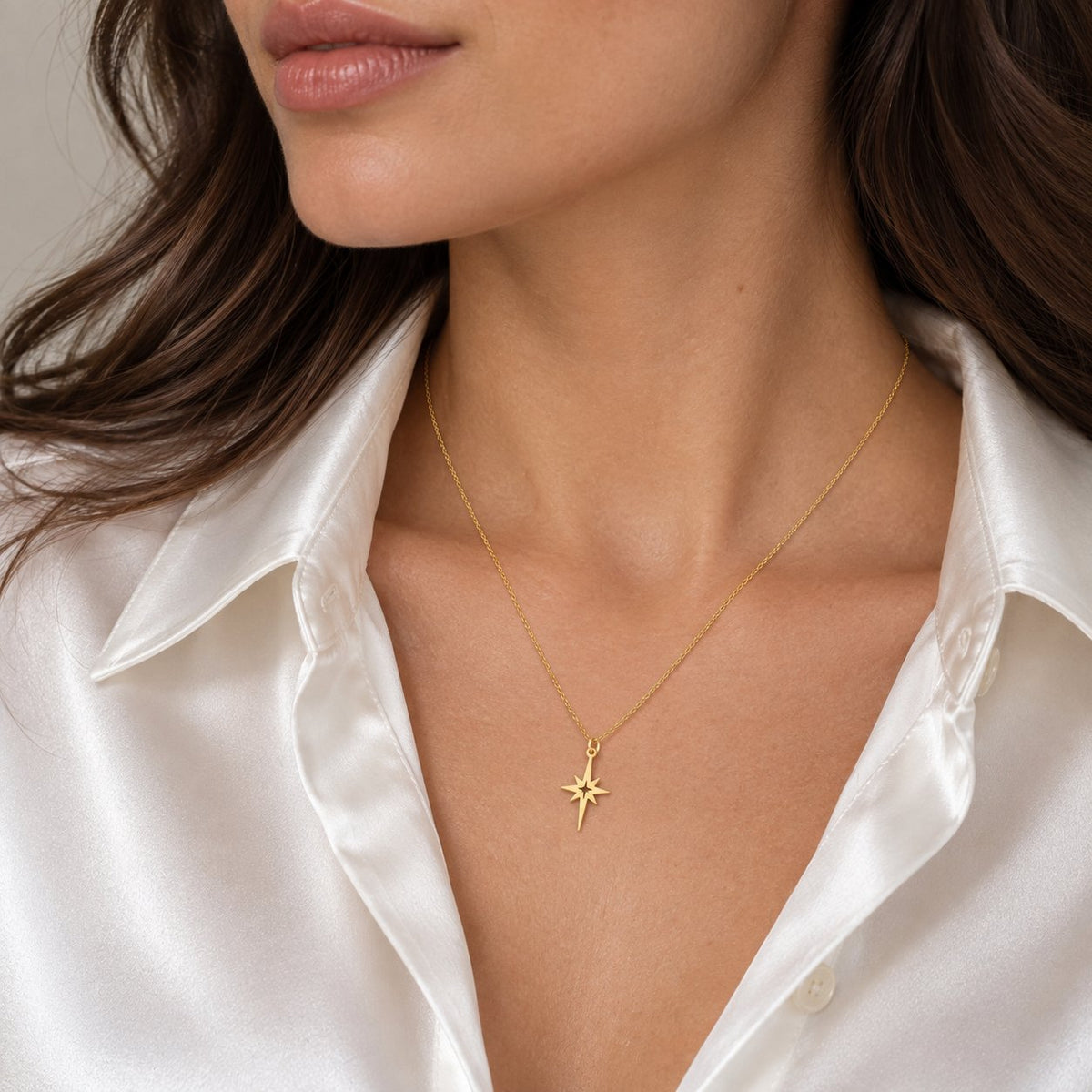 14K solid gold North Star necklace on woman wearing white satin shirt