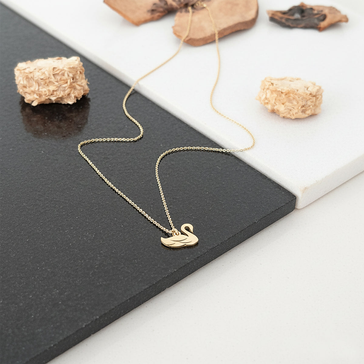 Close-up of 14K yellow gold dainty swan pendant charm necklace