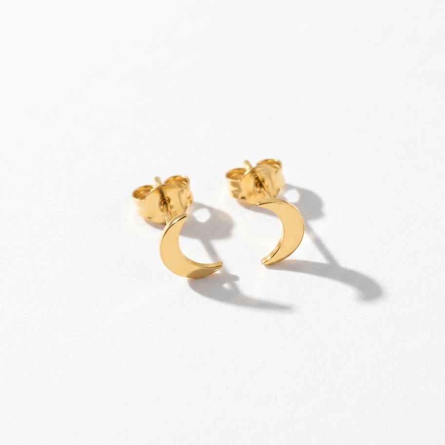 A pair of gold crescent moon stud earrings on a clean white background with soft shadows.