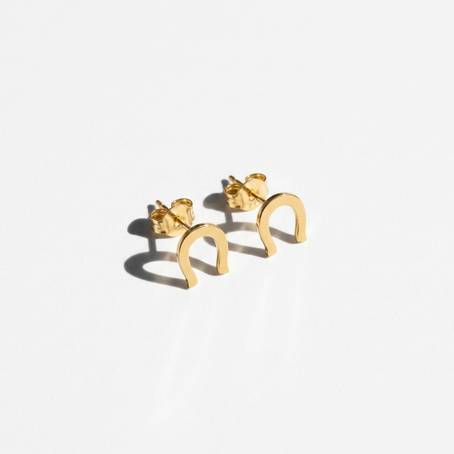 A pair of small gold crescent-shaped hoop earrings with post backs, displayed on a clean white background with soft shadows.