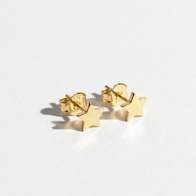 A pair of small gold star-shaped stud earrings on a clean white background.