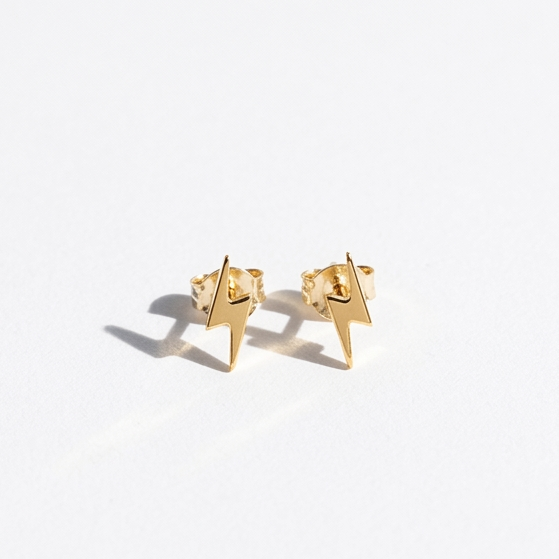 A pair of small gold geometric stud earrings with a star-like or pointed triangular design, photographed on a clean white background with soft shadows.